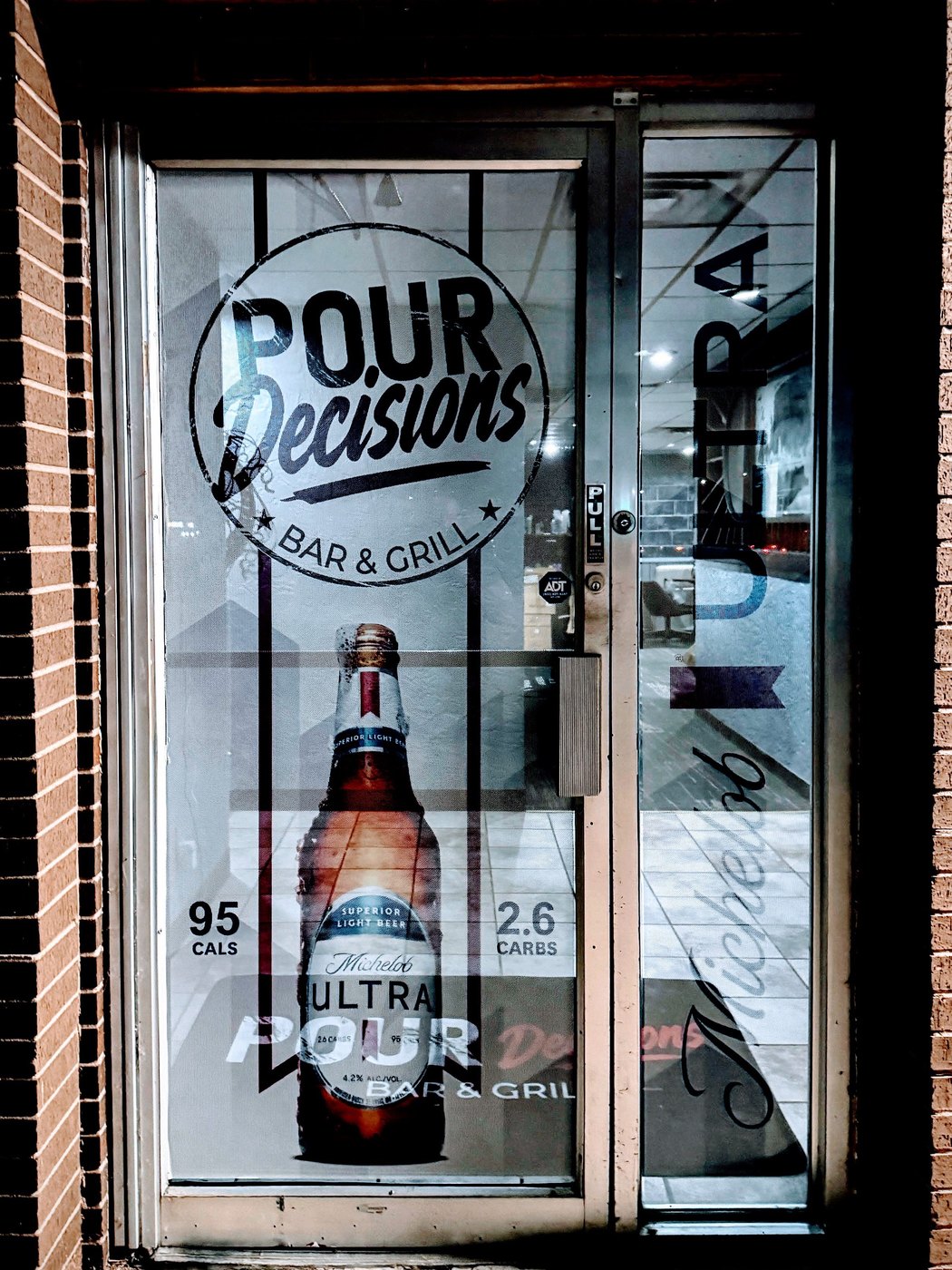 The entry door, cut in a single color on glass. One ink, no glow, no gradient. This is the version the original logo could never have become.